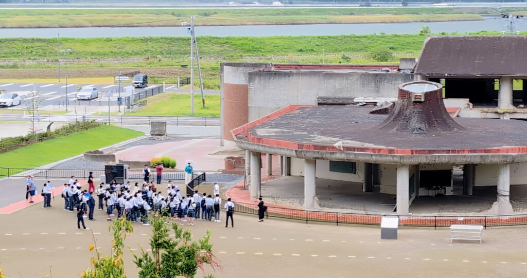 Okawa School Tsunami Memorial – Stories of Hope and Resilience Visitors gathered at Okawa Elementary School ruins, learning about the 2011 tsunami tragedy and its lessons for disaster preparedness.