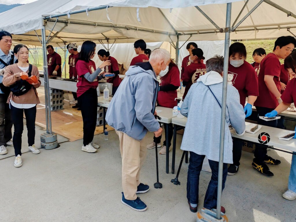 Volunteers serving freshly grilled Pacific saury to visitors at Onagawa Harvest Festival 2025, Miyagi, Japan — a heartfelt exchange of gratitude, warmth, and community. Captured by Japan Lens by GraceyG.