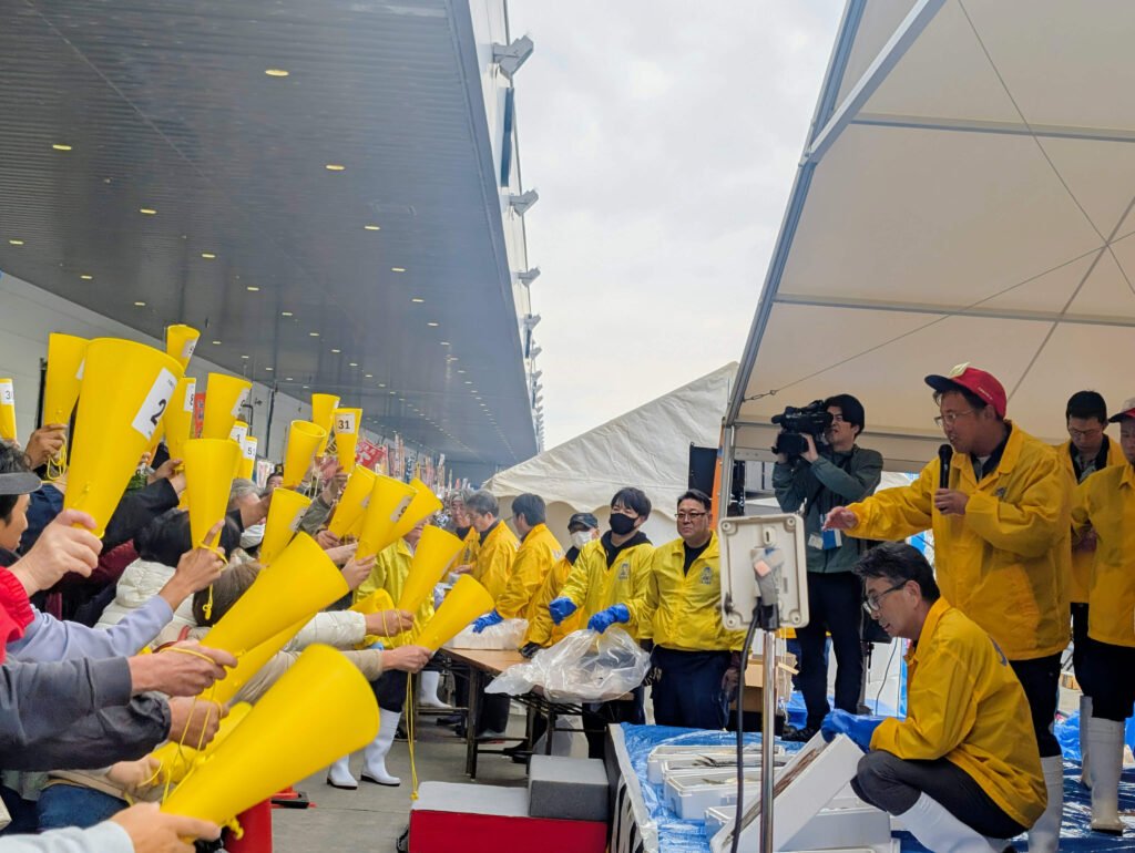 Fish market auction at Ishinomaki Taigyō Matsuri with vendors raising yellow cones