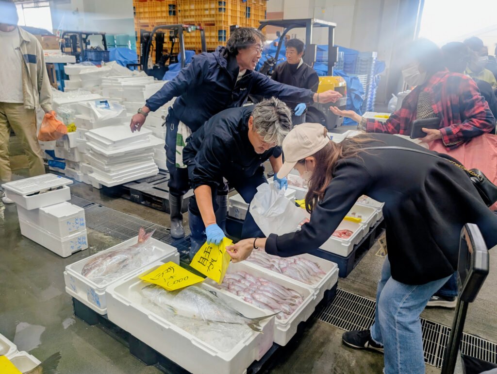 Buyers inspecting fresh seafood and placing bids during the Ishinomaki Taigyō Matsuri auction
